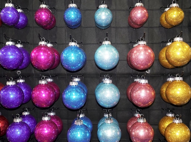 Photo des rangées de boules de noël sont accrochées par couleur à la vente.