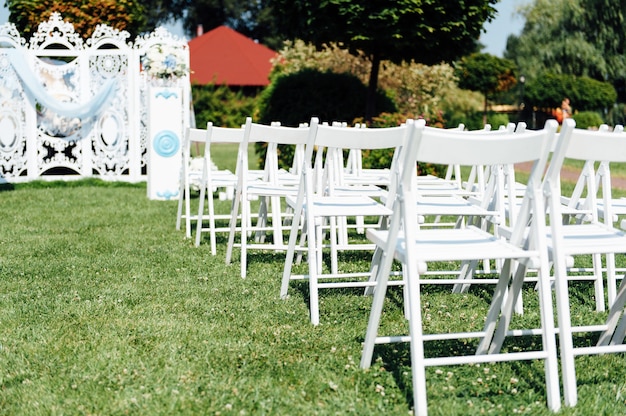 Des rangées de chaises pliantes blanches sur la pelouse