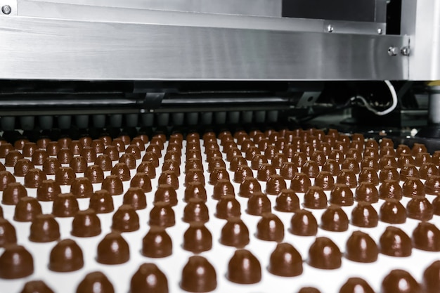 Rangées de garnitures pour chocolats fabriqués à la machine, sur un convoyeur d'une chocolaterie