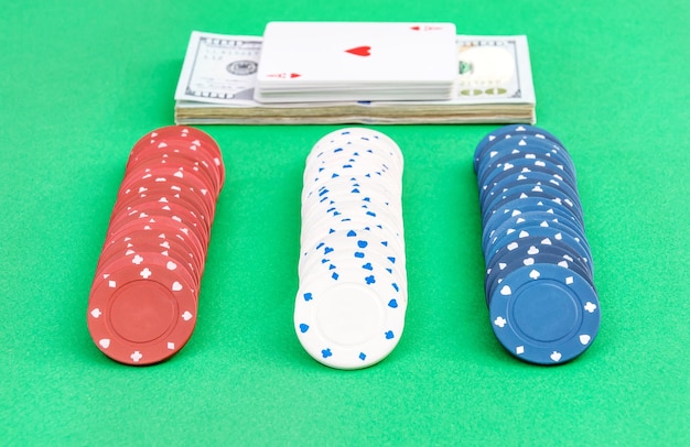 Rangées de jetons de poker avec de l'argent et des cartes sur fond vert