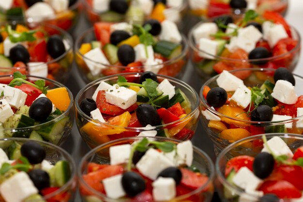 Des rangées de salades grecques en portions avec des légumes frais. Restauration pour réunions d'affaires, événements et célébrations.