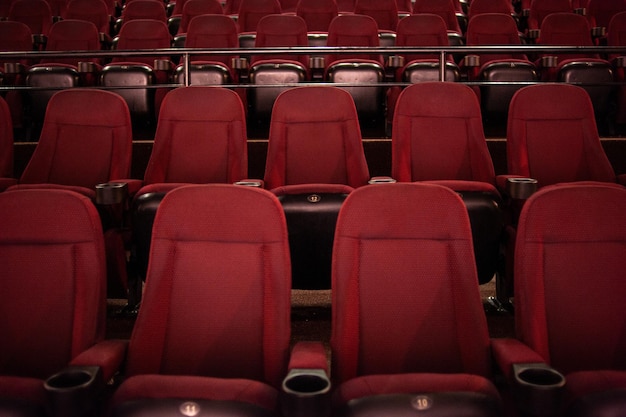 Des rangées de sièges rouges dans un théâtre avec le mot " le mot " sur le devant. "