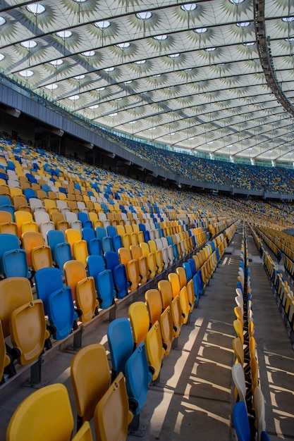 Des rangées de sièges vides dans un stade olympique de football avec des bancs jaunes et bleus