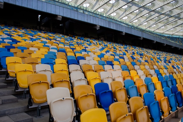 Des rangées de sièges vides dans un stade olympique de football avec des bancs jaunes et bleus