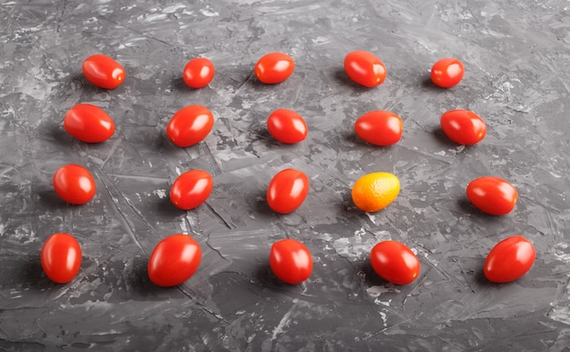 Des rangées de tomates cerises et un kumquat sur fond noir