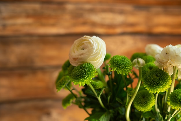 ranunculi blanc et fleurs printanières vertes sur fond en bois.