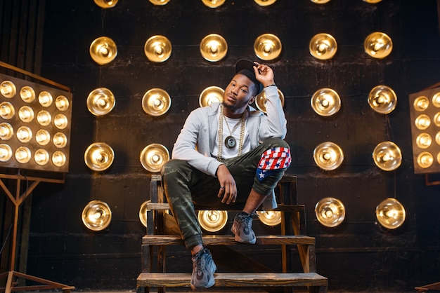 Rappeur noir dans des poses de casquette, performance sur scène avec des projecteurs