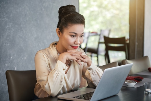 Rapport de lecture concentré d'une femme entrepreneur avec des données de vente sur un écran d'ordinateur portable