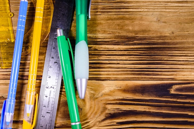 Photo rapporteur de stylos à bille multicolore et règle sur table en bois rustique vue de dessus