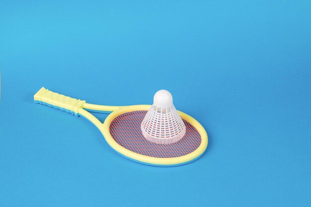 Une raquette de badminton jaune pour les enfants et un volant blanc sur fond bleu