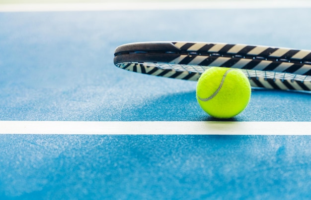 Raquette et balle de padel sur le court bleu Photo horizontale