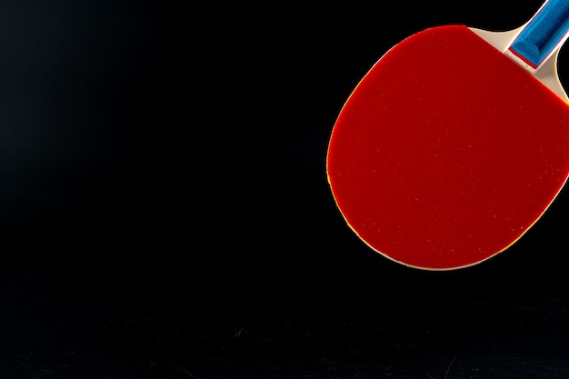 Raquette de ping-pong rouge sur fond sombre. Équipement sportif