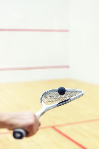 raquette de squash et balle dans la main des hommes