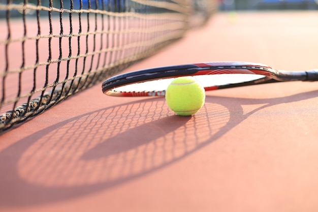 Raquette de tennis et balle sur court de tennis.