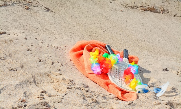 Raquettes et lunettes avec une serviette orange sur le sable