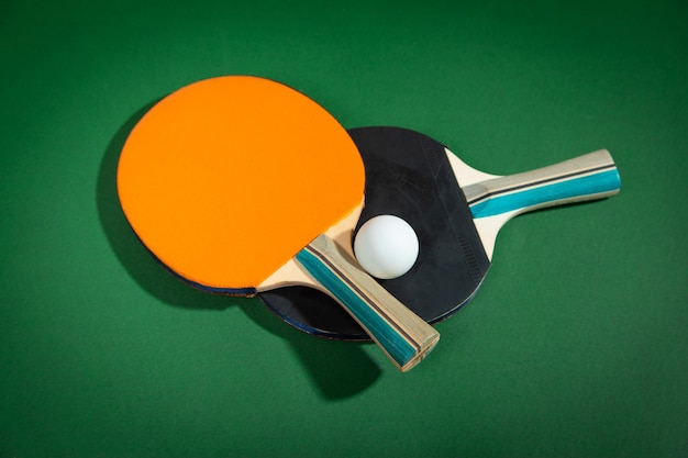 Raquettes de ping-pong et une boule en plastique blanche sur le fond vert