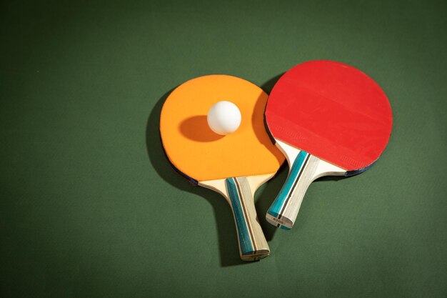 Raquettes de ping-pong et une boule en plastique blanche sur le fond vert