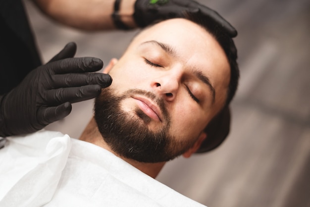 Rasage d'une barbe dans un salon de coiffure avec un rasoir dangereux.