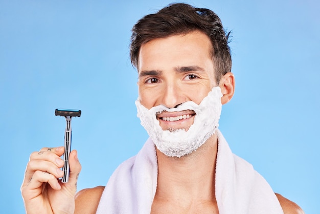 Rasoir homme et rasage avec crème heureux et soins de la peau tout en toilettant la barbe matin et cosmétique sur fond de studio bleu avec maquette Sourire propre et modèle nettoyant les poils du visage pour une beauté naturelle