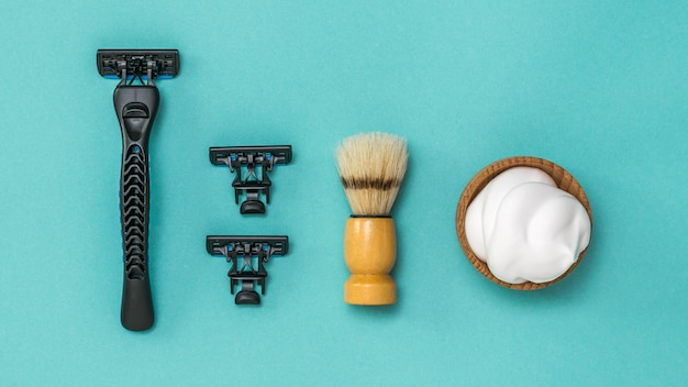 Photo rasoir noir avec deux lames de rechange et une brosse de rasage pour le rasage sur fond bleu. set pour le soin du visage d'un homme. mise à plat.