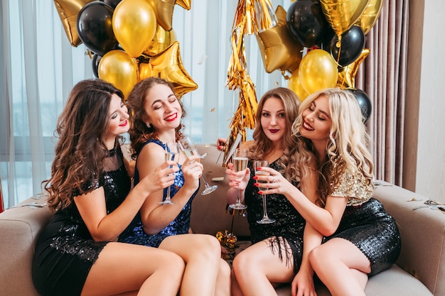 Rassemblement de filles. Événement spécial. Mesdames traînent, profitant d'une fête à la maison avec du champagne et des conversations amusantes.