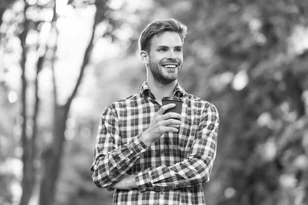 Ravi d'être ici beau mec porter une chemise à carreaux et tenir une tasse de thé en papier homme buvant du café pour aller en plein air homme se rafraîchir mal rasé étudiant heureux boire du café du matin bonjour inspiration