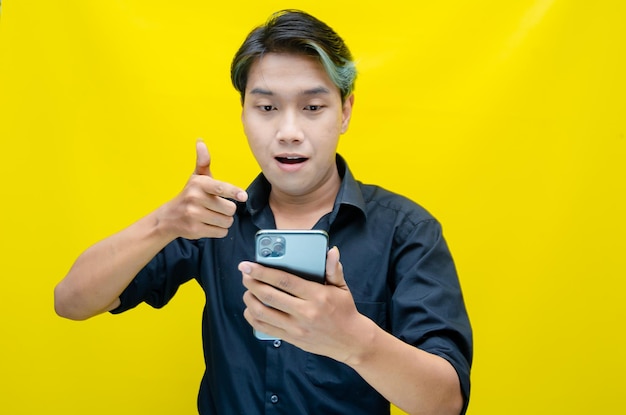 ravi jeune homme asiatique avec peek a boo cheveux colorés portant une chemise noire tenant le téléphone