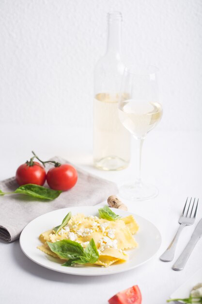 Raviolis bouillis au basilic, fromage et tomates sur tableau blanc