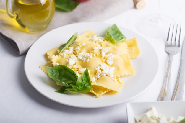 Raviolis bouillis au basilic, fromage et tomates sur tableau blanc