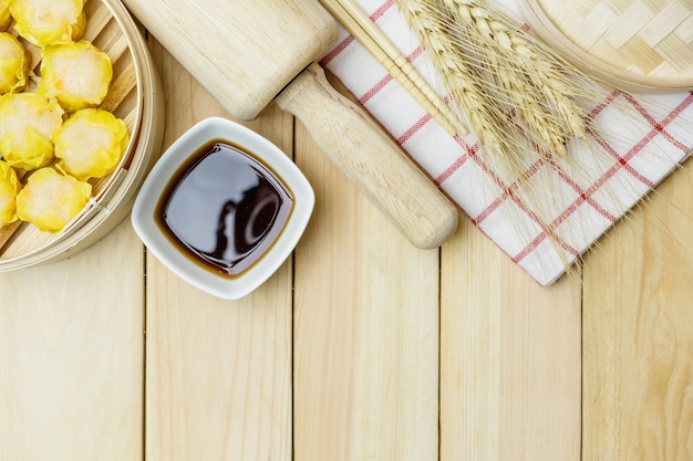 Raviolis cuits à la vapeur (dim sum chinois) dans un panier de bambou sur fond de table en bois