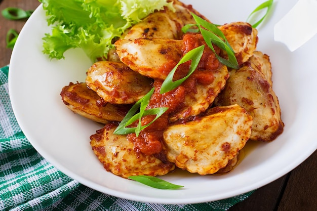 Des raviolis délicieux avec de la sauce tomate et des oignons verts