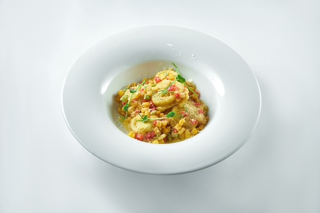 Raviolis italiens avec diverses garnitures (viande, fromage) avec salsa de légumes et parmesan dans une assiette blanche sur une assiette blanche