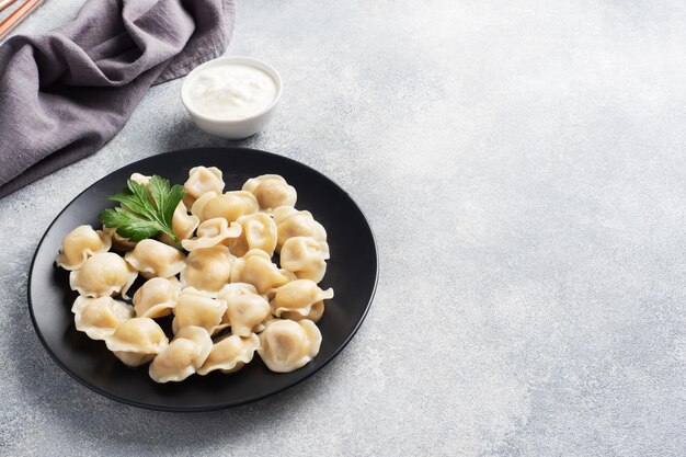 Raviolis pelmeni traditionnels boulettes remplies de viande sur plaque cuisine russe fond béton clair copie espace