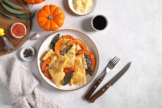 Raviolis de potiron faits maison avec du fromage ricotta servis au beurre de sauge et au fromage sur une assiette sur une table en béton