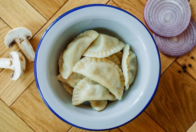 Raviolis de raviolis de pelmeni russes faits maison bouillis avec de la viande sur une assiette grise avec du persil frais et du poivre fond rustique en bois vue de dessus