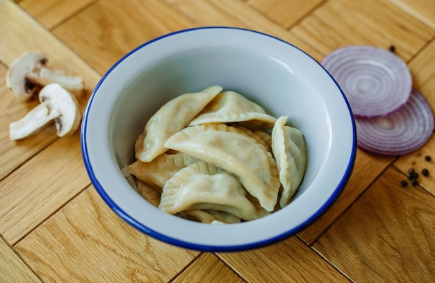 Raviolis de raviolis de pelmeni russes faits maison bouillis avec de la viande sur une assiette grise avec du persil frais et du poivre fond rustique en bois vue de dessus