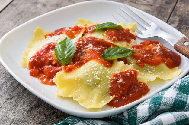 Raviolis à la sauce tomate et basilic sur fond de bois.