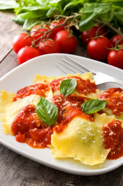 Raviolis à la sauce tomate et basilic sur fond de bois.