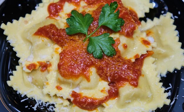 Raviolis à la tomate, au fromage et au persil sur une plaque noire, vue aérienne