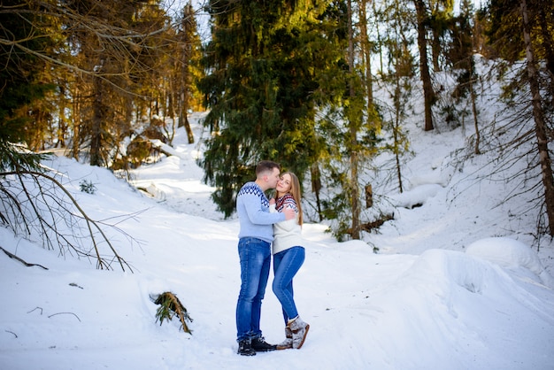 Ravissant couple s'embrassant dans la forêt d'hiver.