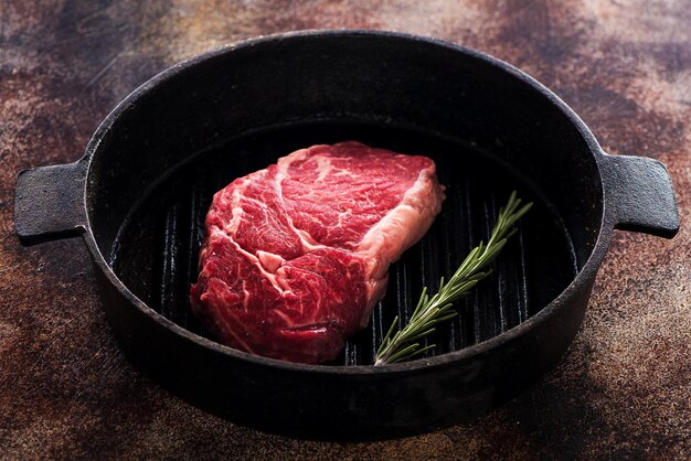 Raw Beef Steak Ribeye au romarin dans une poêle en fonte