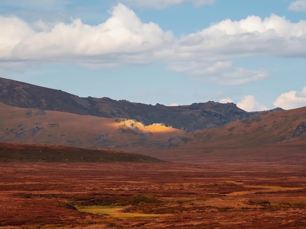 Rayon de soleil étroit et lumineux sur une pente de montagne sombre Paysage de montagne atmosphérique avec de gros rochers sous un ciel nuageux Lumière mystique dans les montagnes sombres et brumeuses Ciel dramatique sur les sommets des montagnes