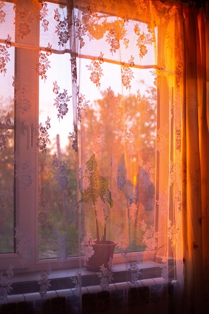 Les rayons du soleil au coucher du soleil brillent à travers la fenêtre illuminant la maison d'une lueur chaleureuse