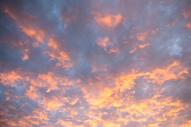 Les rayons orange vif du soleil couchant illuminent les nuages dans le ciel bleu du soir