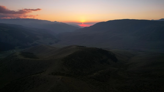 Rayons rouges du soleil au coucher du soleil parmi les montagnes