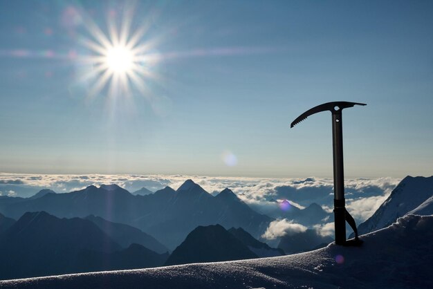 Rayons de soleil avec piolet ou outil et chaîne de montagnes en arrière-plan.