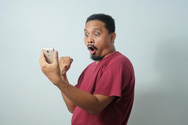 Réaction étonnée d'un homme asiatique en regardant le téléphone