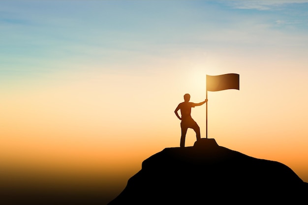 Réalisation de leadership de réussite commercialeSilhouette d'homme d'affaires avec le drapeau sur l'heure du coucher du soleil de la montagne