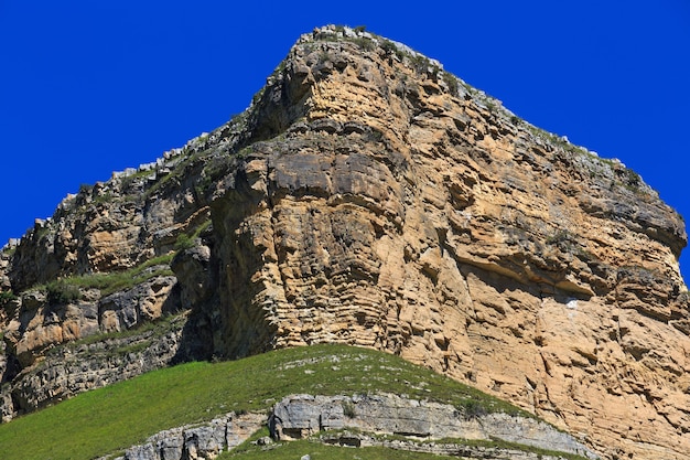 Rebord en pierre d'une crête rocheuse contre le ciel bleu.