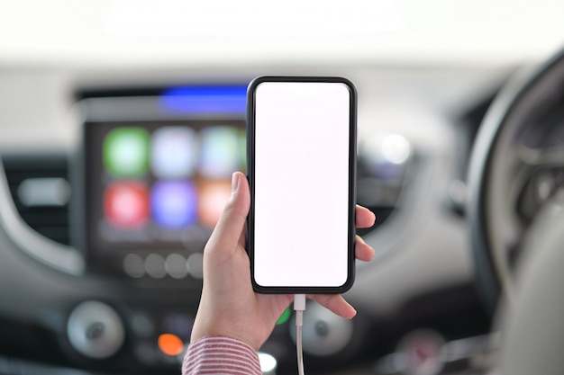 Recadré coup de main féminine tenant un téléphone portable dans la voiture.